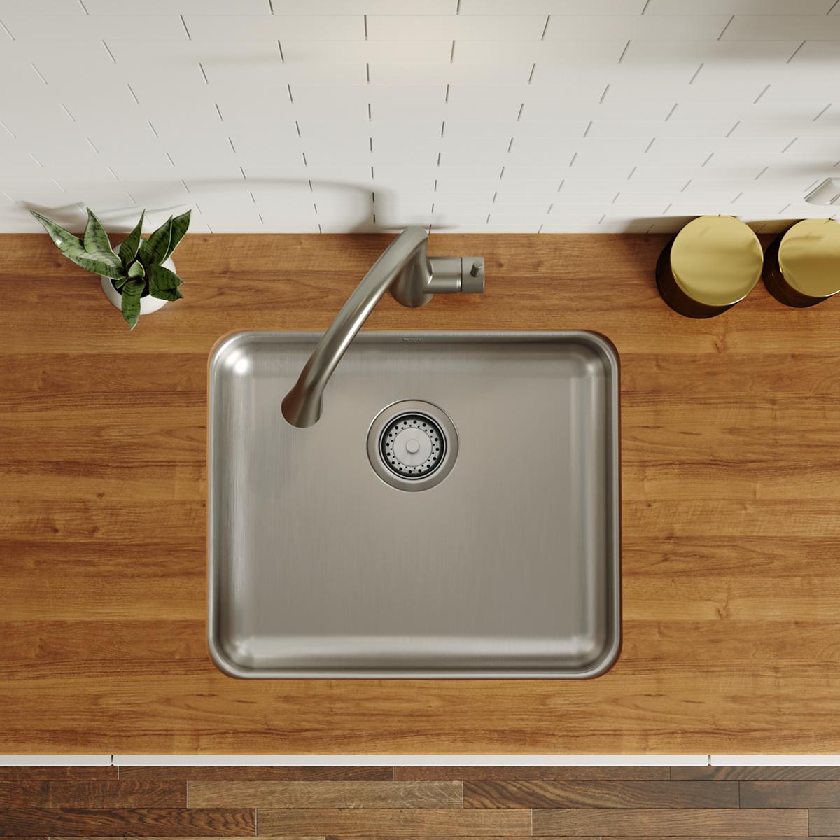 Stainless steel single bowl undermount sink with drain and faucet installed in wood countertop.