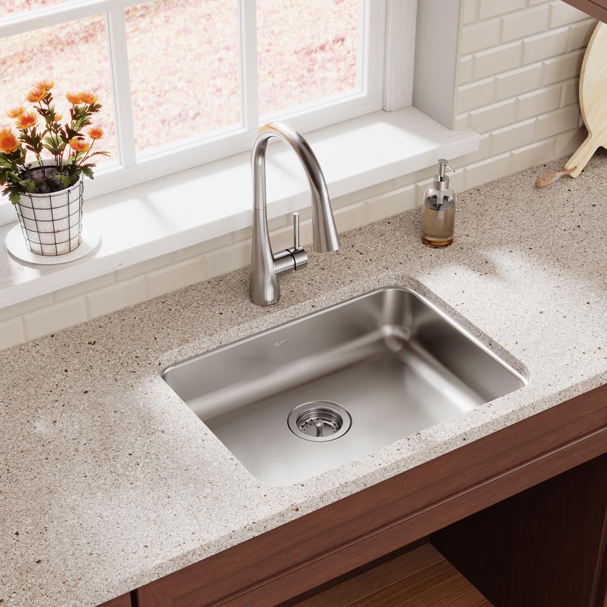 Stainless steel single bowl undermount sink installed in gray quartz countertop with chrome faucet.