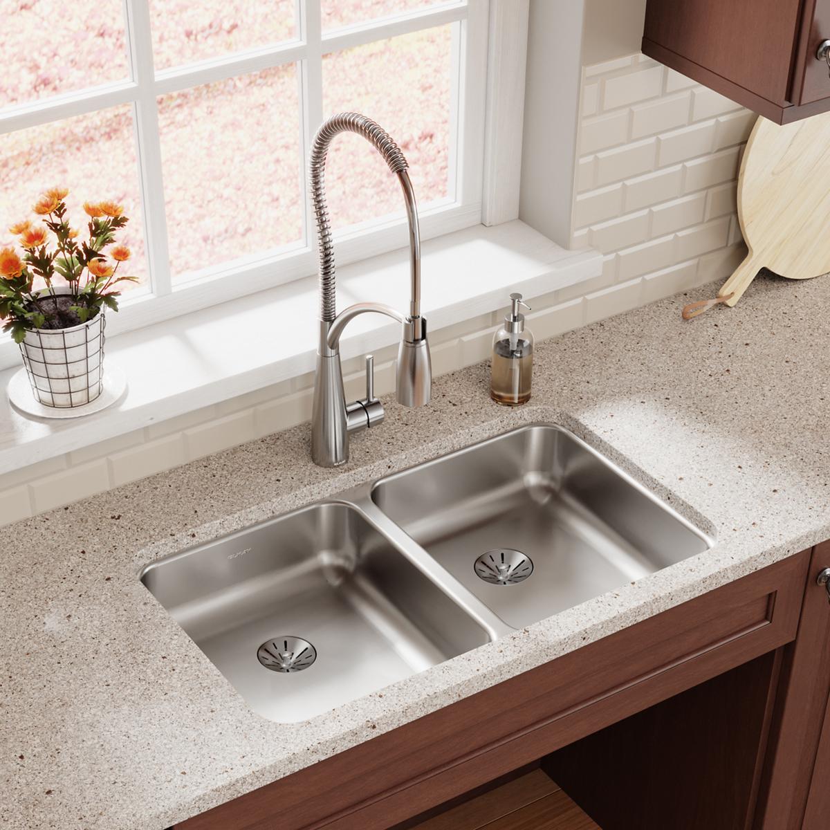 Stainless steel double bowl undermount sink installed in countertop with chrome pull-down faucet and drain strainers.