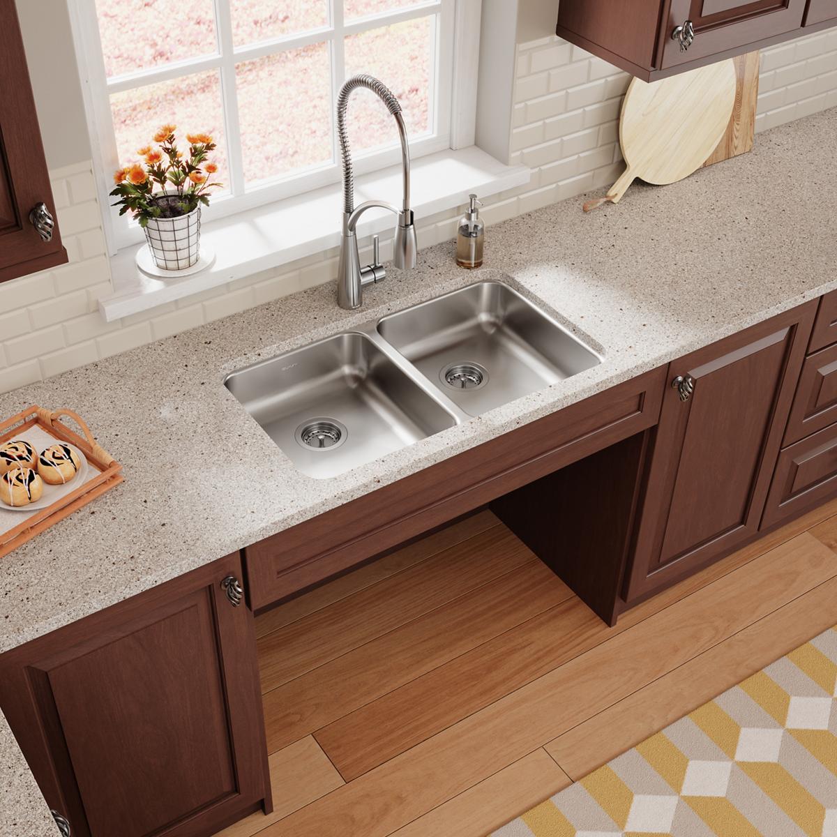 Stainless steel double bowl undermount sink installed in quartz countertop with chrome faucet.