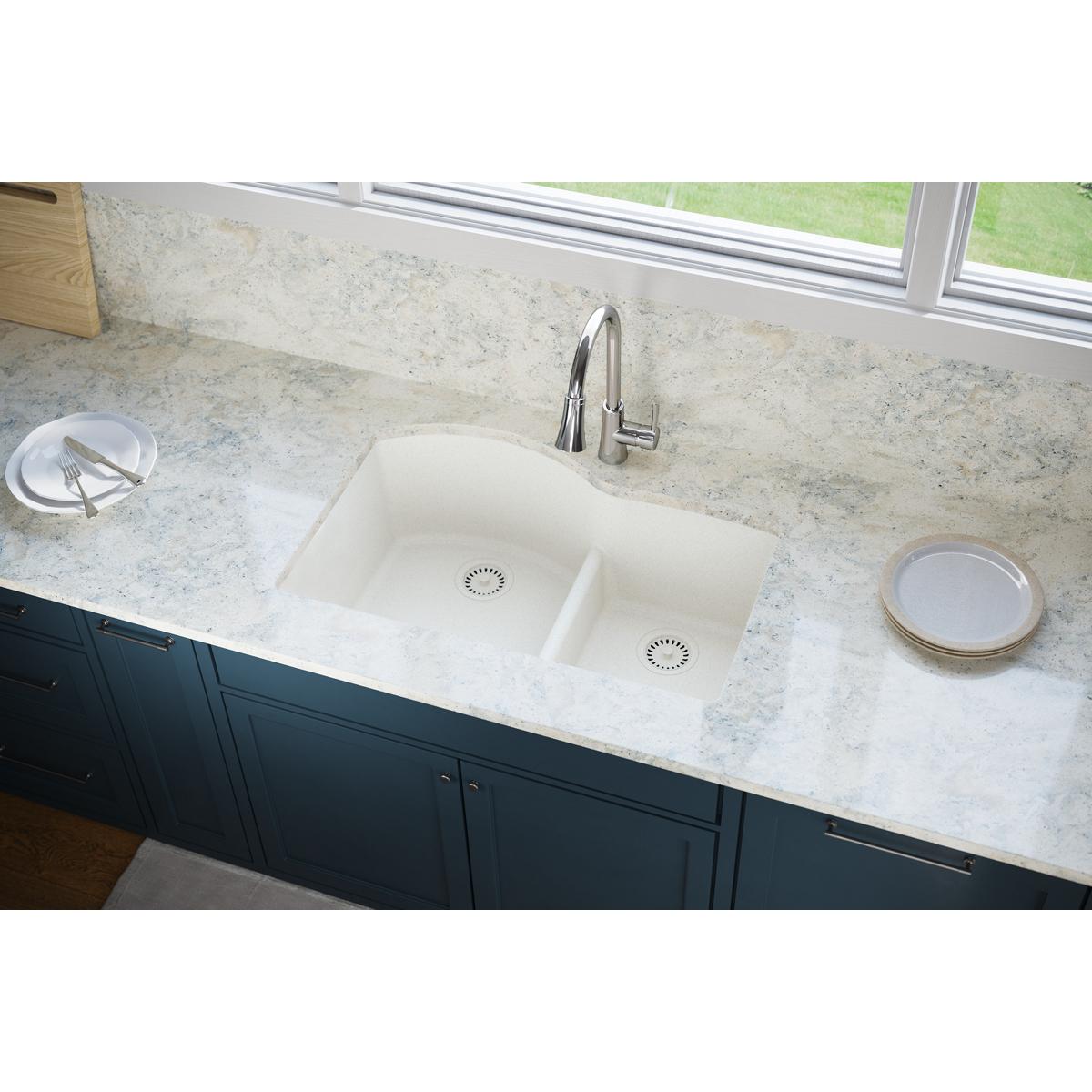 Ricotta-colored polymer drain fitting with removable basket strainer installed in white double-bowl kitchen sink.