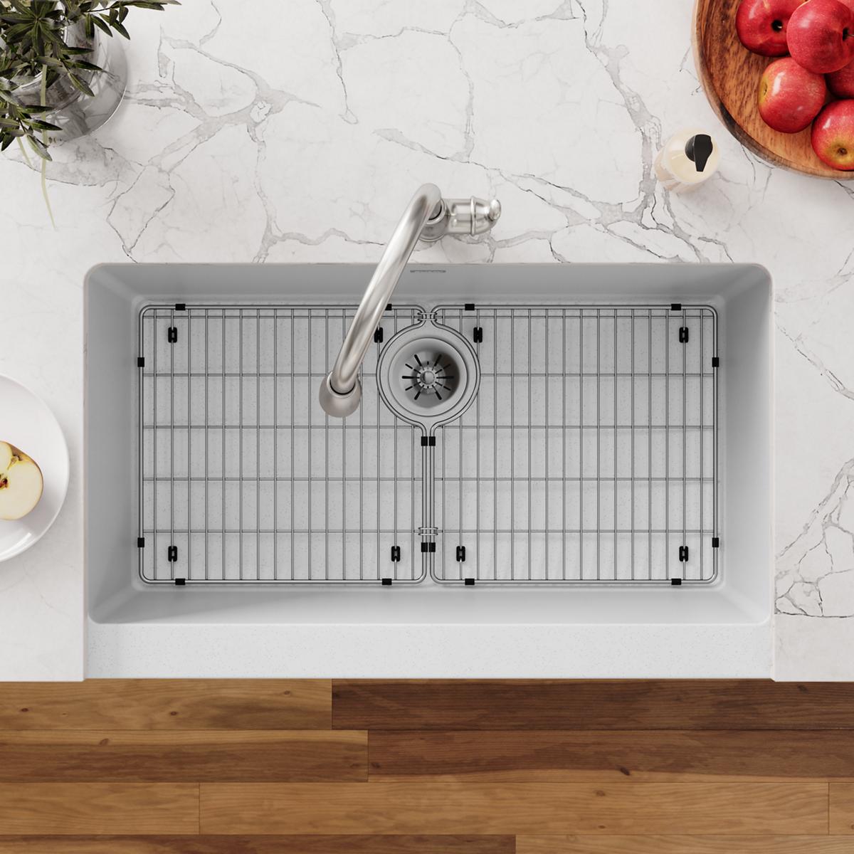 Stainless steel sink grid with vertical slat pattern and black rubber feet, shown installed in double-basin sink.