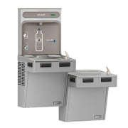 Light gray Elkay water filling station with upper bottle fill spout and lower dual drinking fountains with push buttons.