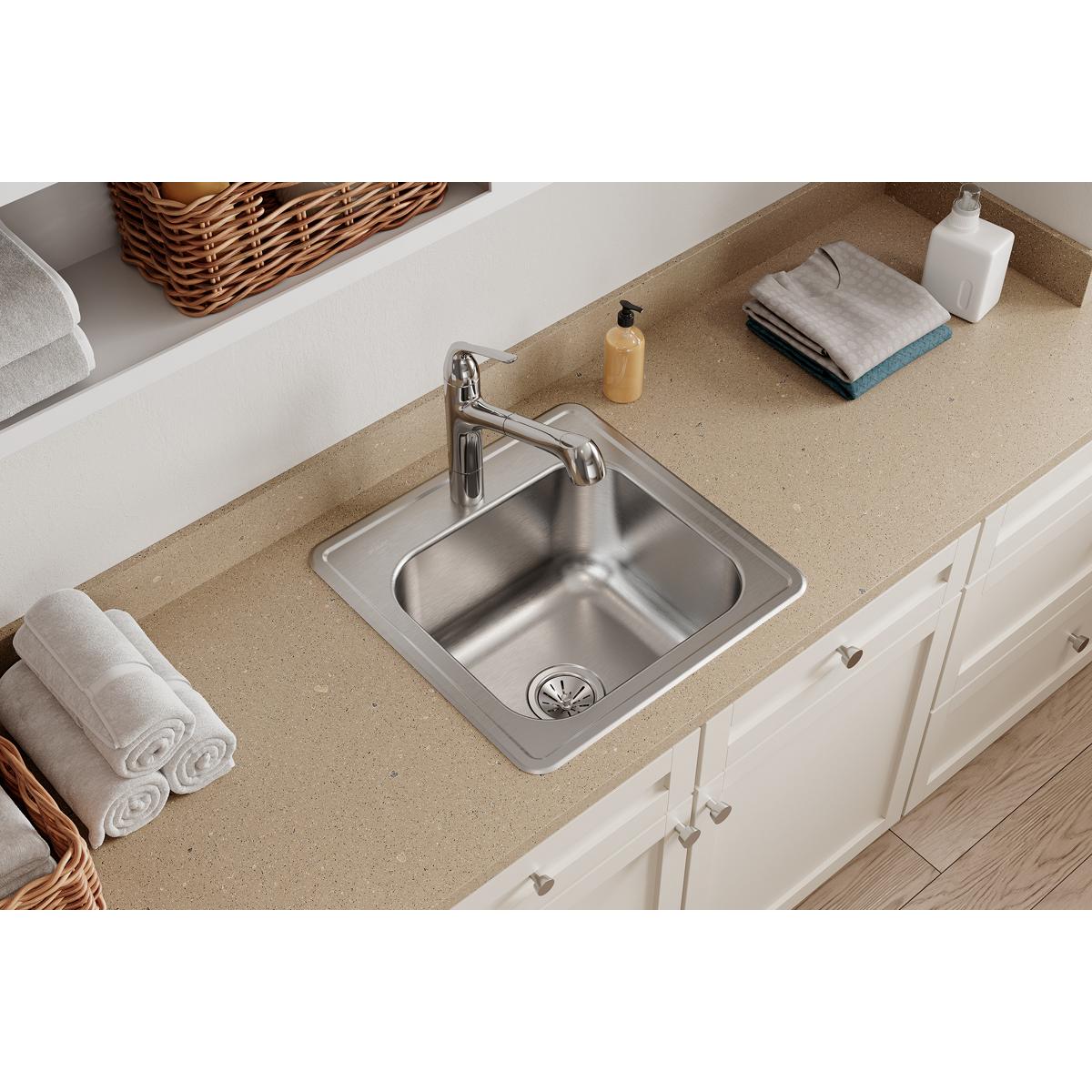 Stainless steel drop-in laundry sink with single bowl installed in beige countertop next to chrome faucet.