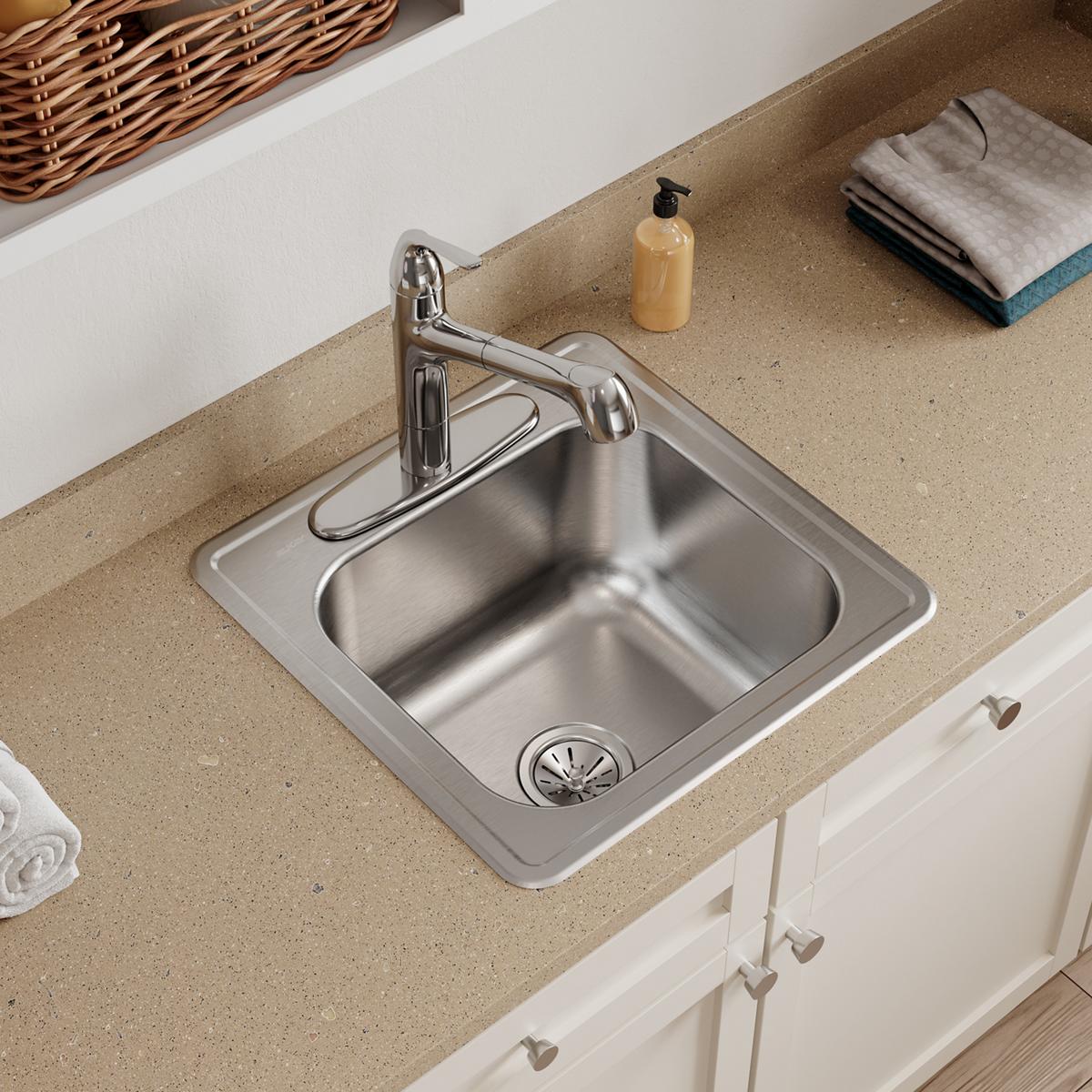 Stainless steel square drop-in laundry sink with single bowl, drain basket, and chrome faucet installed in tan countertop.