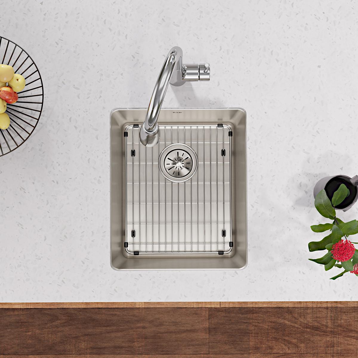 Stainless steel sink grid with vertical bar pattern and rubber corner feet, shown installed in undermount sink.