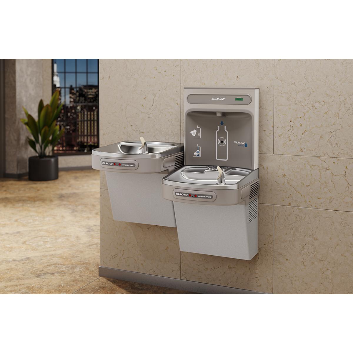 Light gray Elkay ezH2O dual-level water filling station mounted on beige tile wall with two fountain basins and hands-free ac