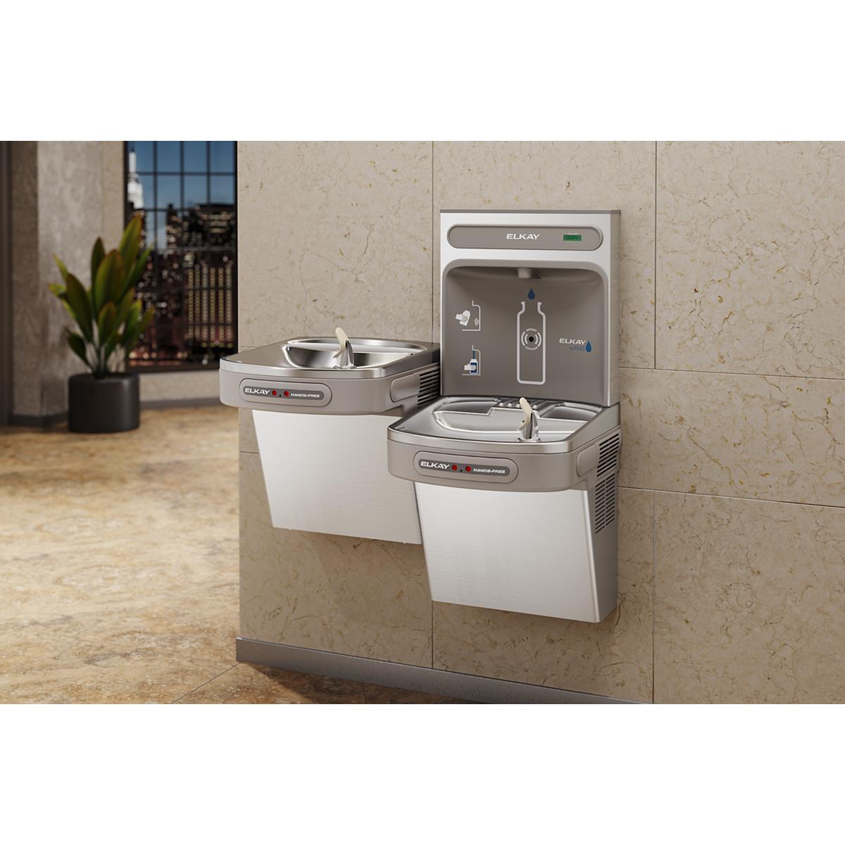 Stainless steel dual-level water filling station mounted on beige tile wall with upper and lower fountain basins and hands-fr