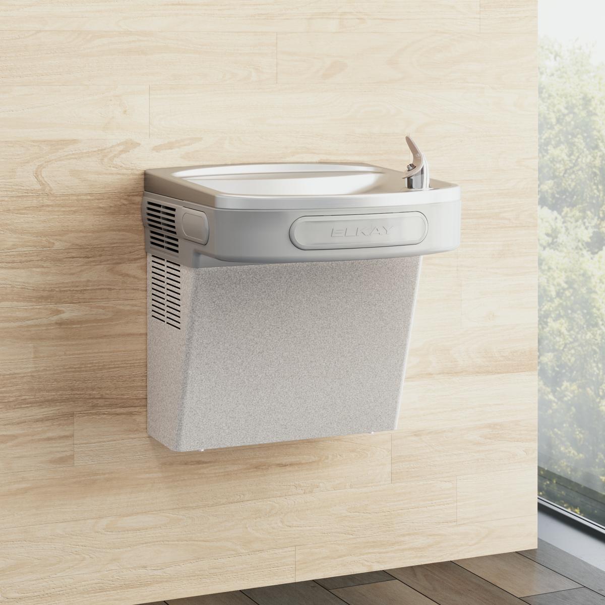 Wall-mounted light gray granite water cooler with white basin and mechanical controls mounted on light wood wall.