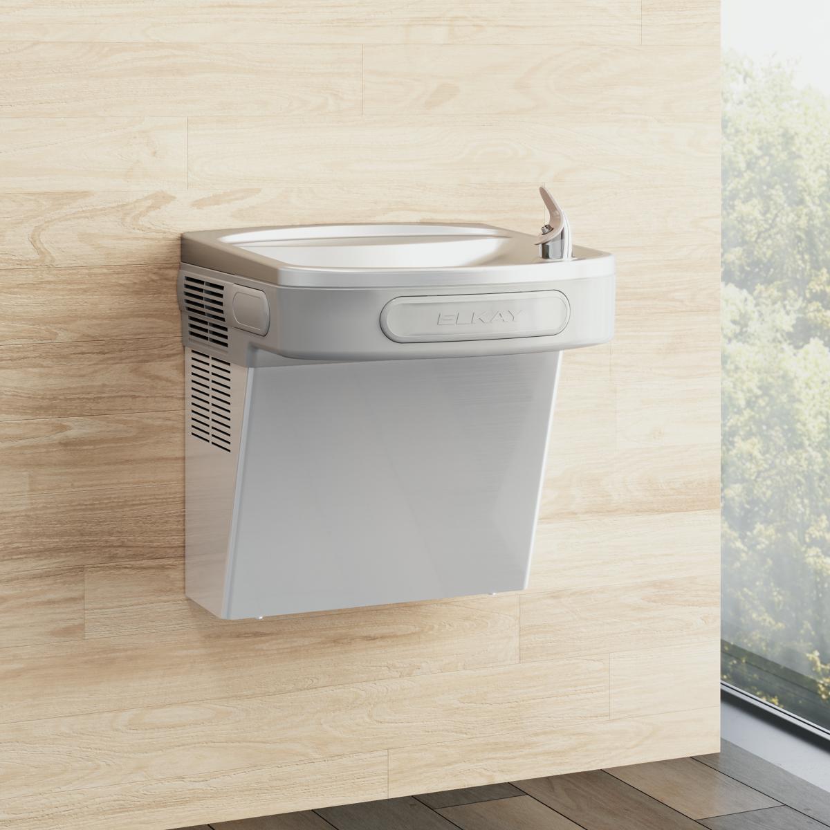 White wall-mounted drinking fountain with stainless steel basin and single lever handle mounted on light wood wall.