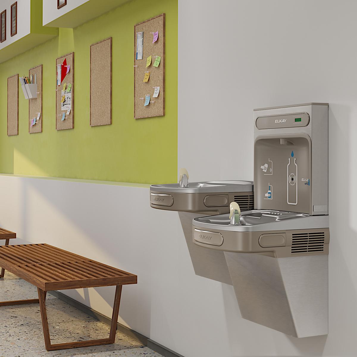 Stainless steel wall-mounted water station with two filling levels and bottle filler opening, installed in office hallway.