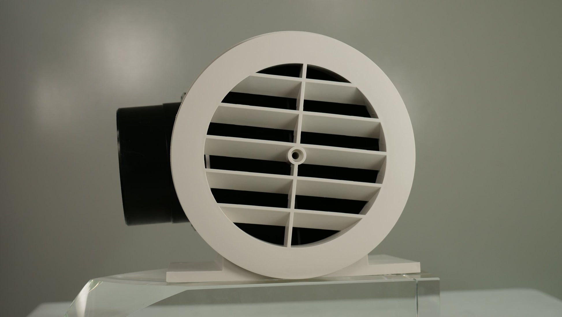 White round soffit vent termination with horizontal louvers and black ducting connector.