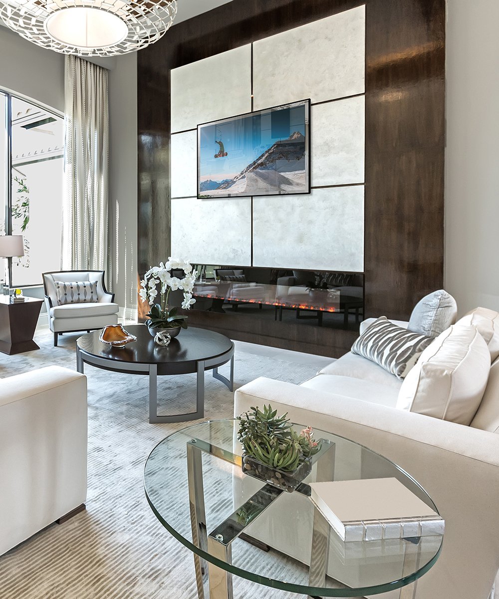 Flat-screen TV mounted on white tile wall panel displaying mountain landscape scene in modern living room.
