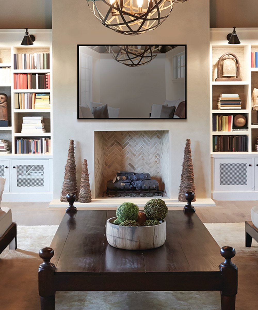 Black-framed television mounted on wall above fireplace in living room with built-in shelving on either side.