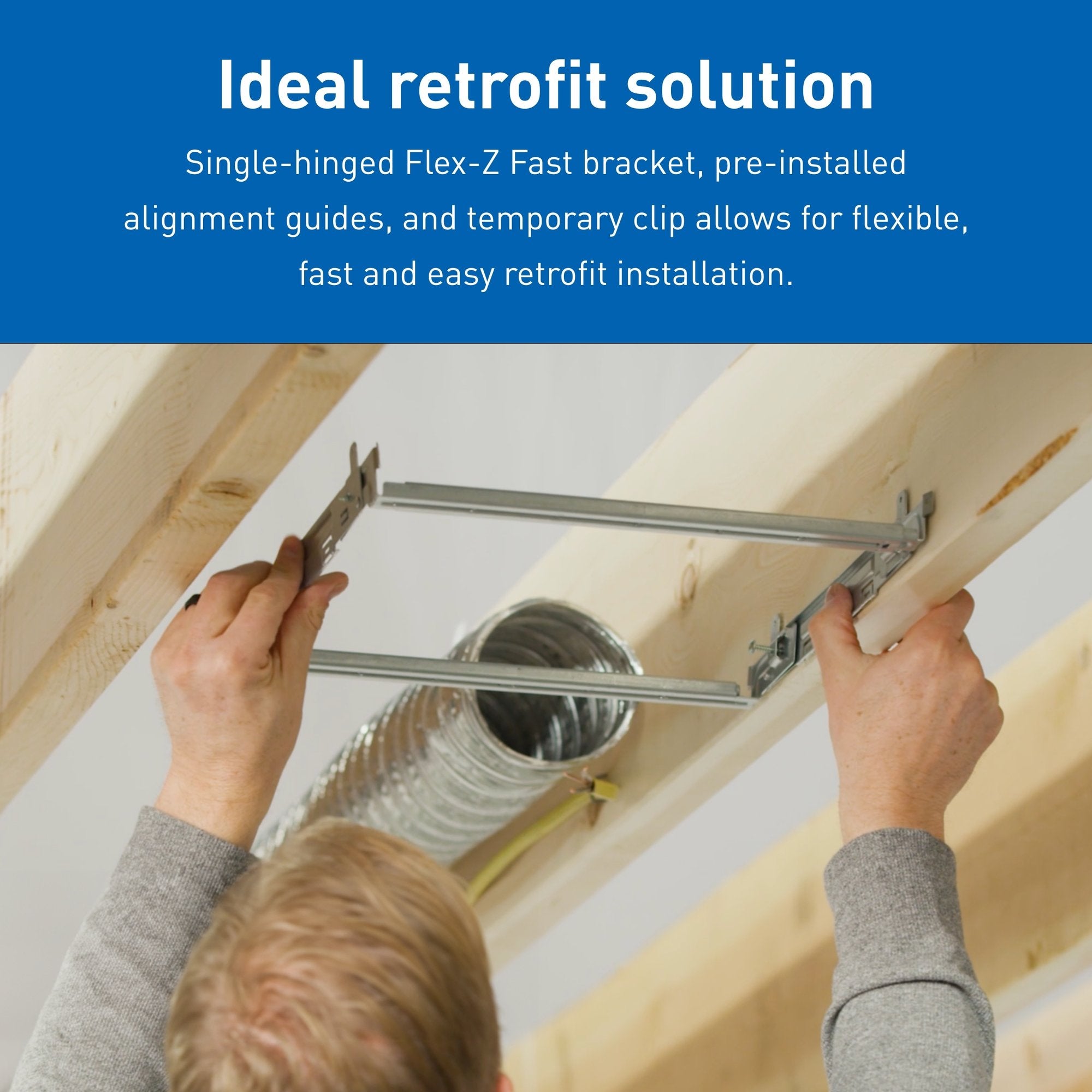 Hands installing metal mounting bracket for ceiling fan between wooden ceiling joists.