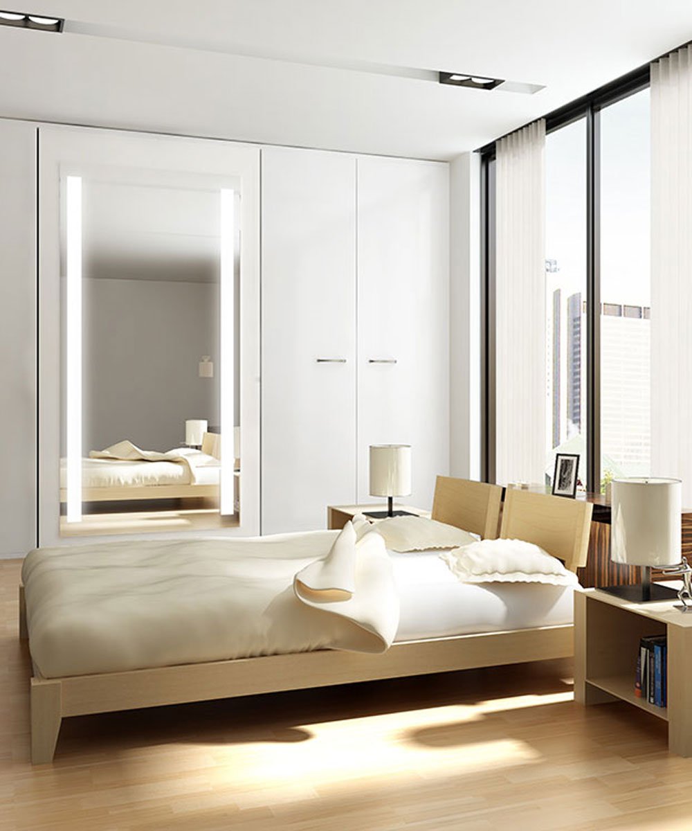 Lighted mirror with vertical LED strips on either side, integrated into white wardrobe doors in a modern bedroom setting.