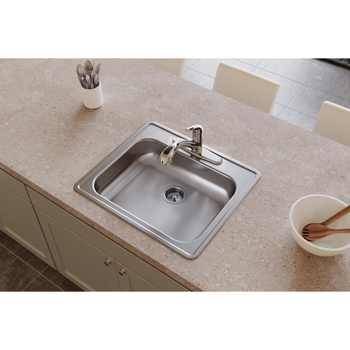 Stainless steel drop-in sink with single bowl, drain, and faucet installed in countertop.