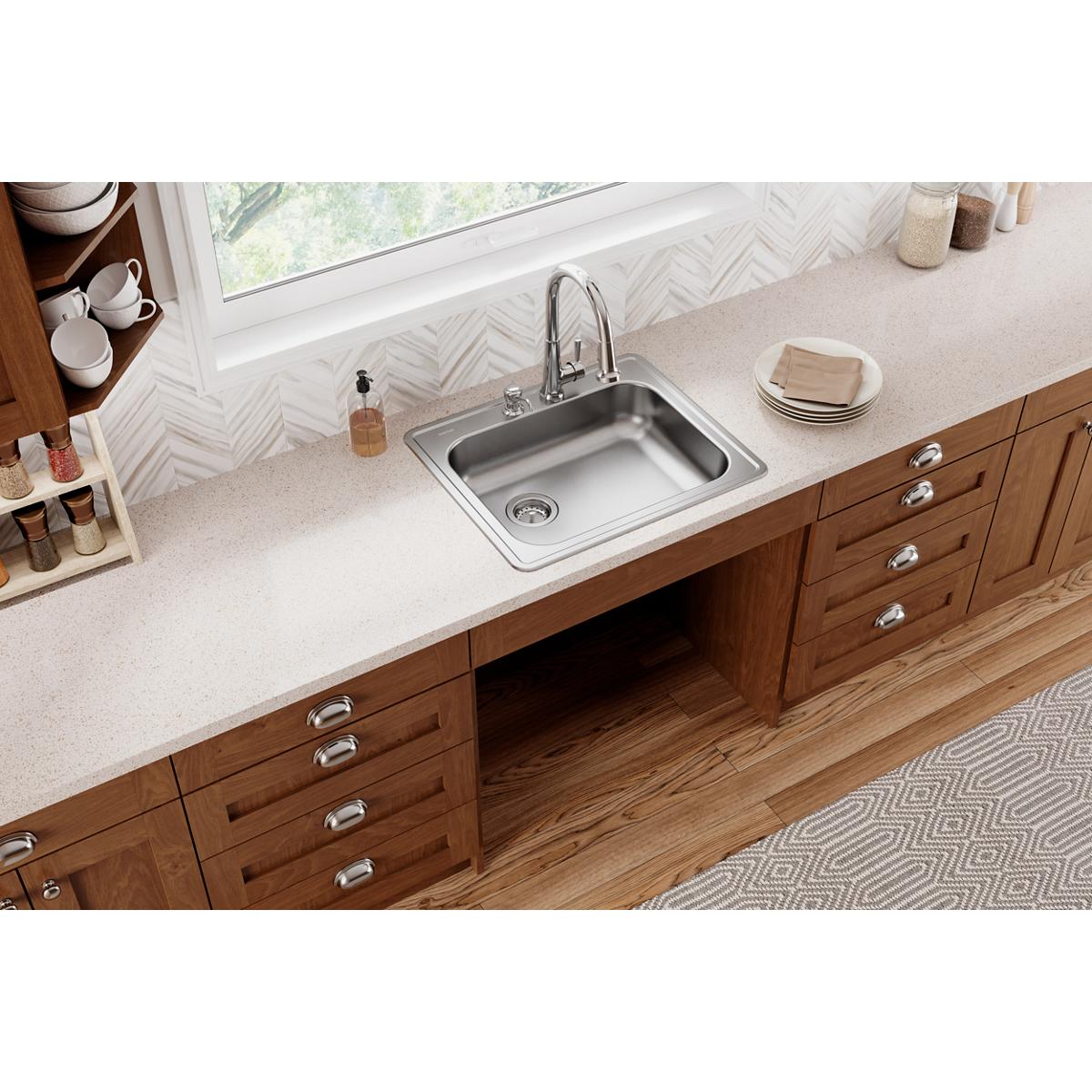 Stainless steel drop-in kitchen sink with single bowl, two faucet holes, and left drain installed in wood cabinetry.