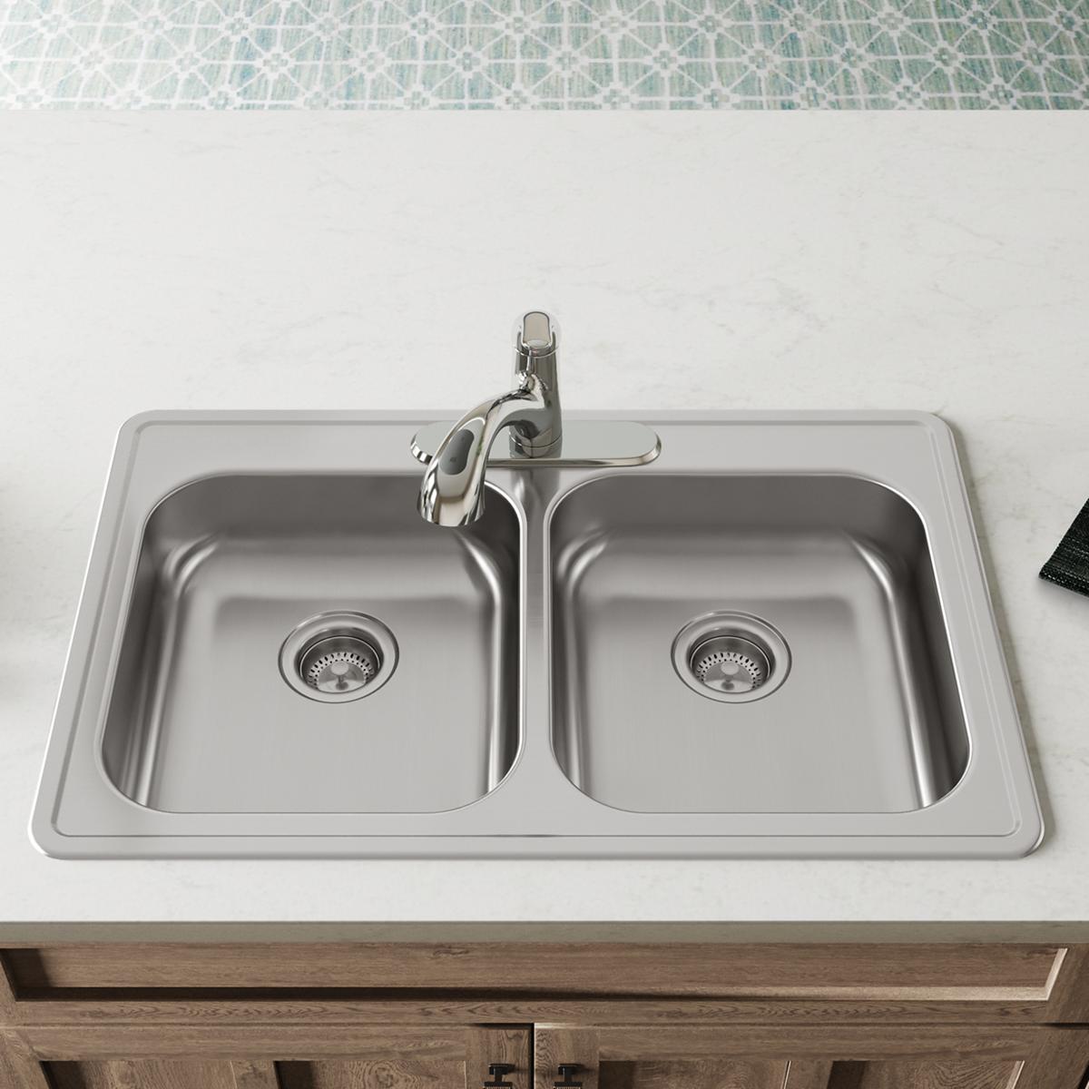 Stainless steel double bowl drop-in sink with two equal basins, drain strainers, and chrome faucet mounted on countertop.