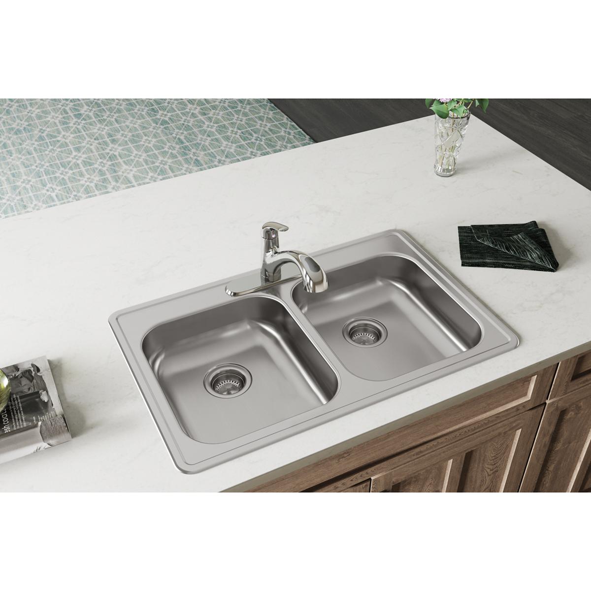 Stainless steel double bowl drop-in sink with chrome faucet installed in white countertop above wood cabinetry.