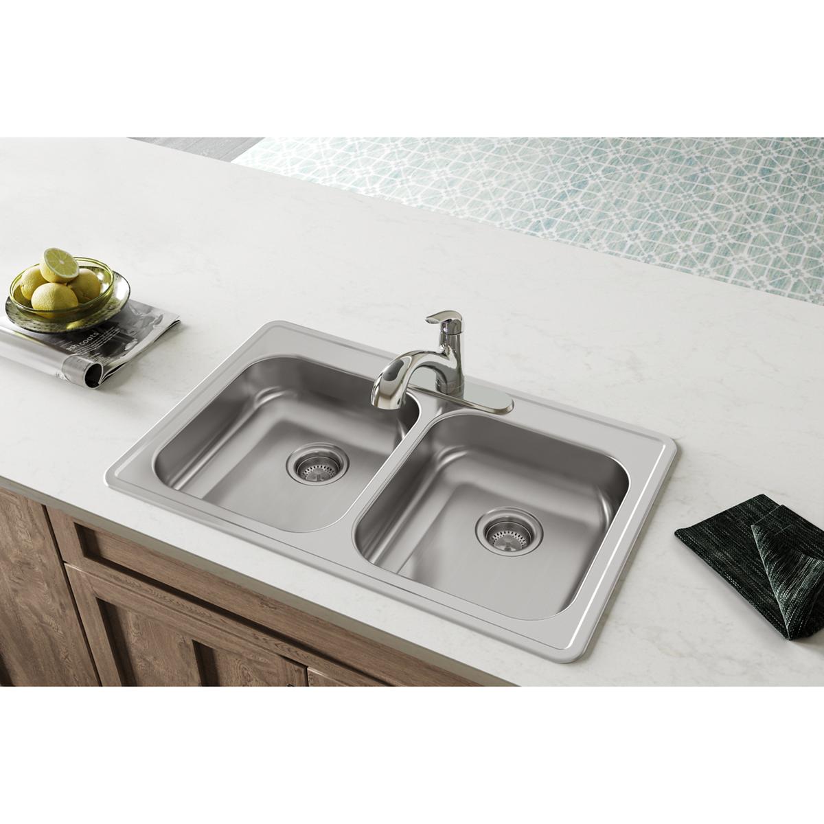 Stainless steel drop-in double bowl sink with two equal compartments, drain strainers, and single faucet mounted on white cou