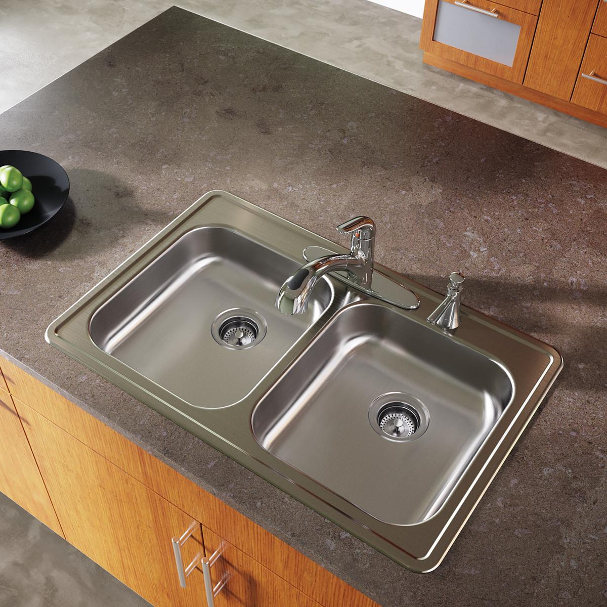 Stainless steel double bowl drop-in sink with two faucets and drain strainers installed in gray countertop.
