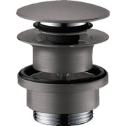 Brushed black chrome push-open sink drain with flat cap and cylindrical body, shown disassembled to display internal componen