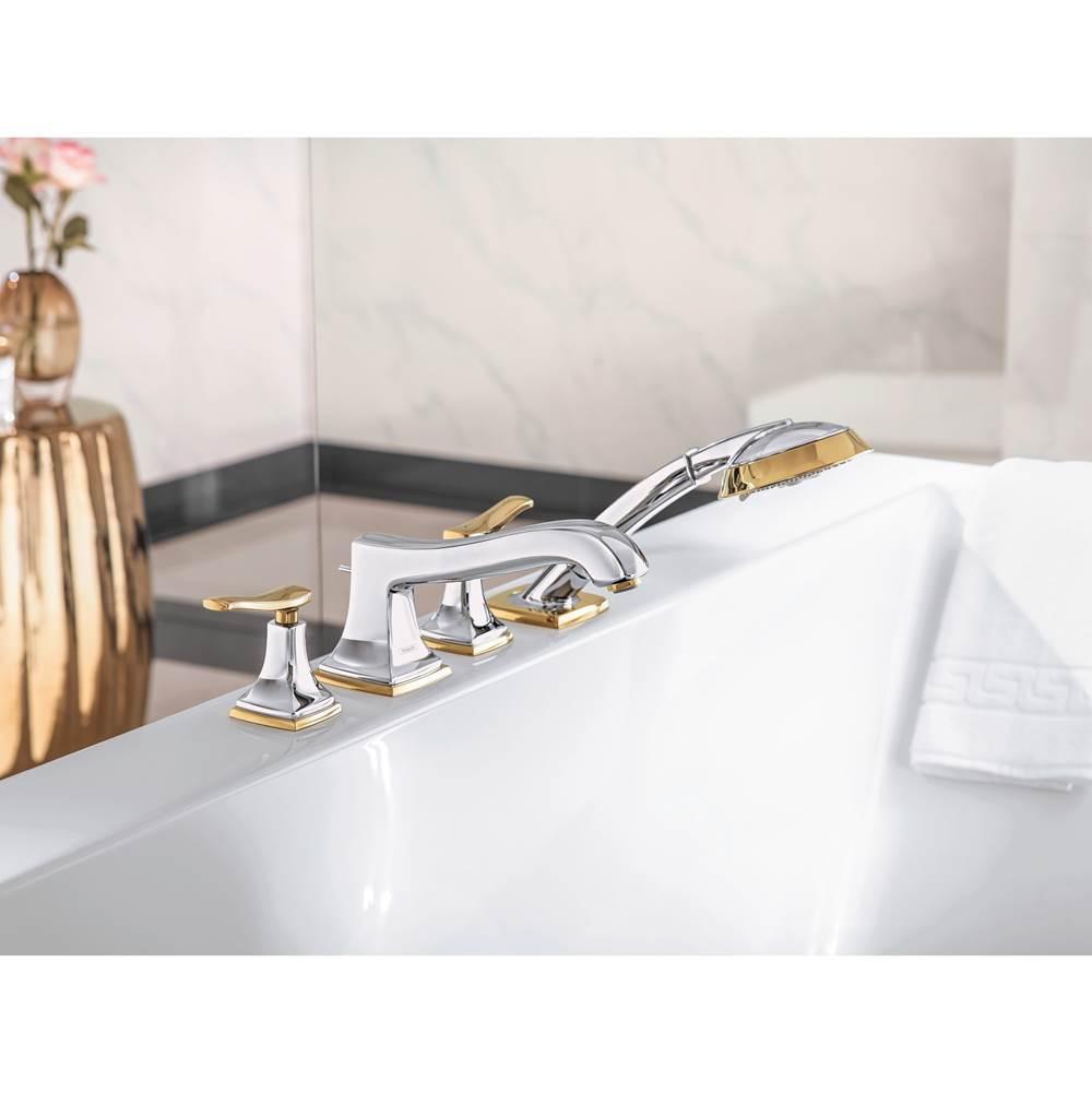 Matte black and gold four-hole roman tub faucet with lever handles and handheld showerhead mounted on white bathtub rim.
