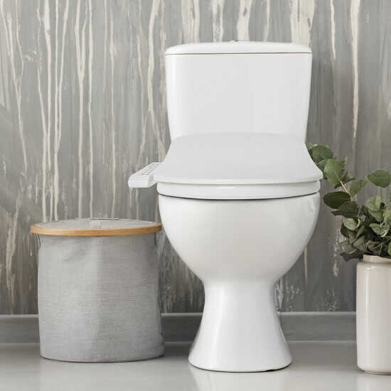 White round bidet toilet seat with attached tank displayed in bathroom setting with gray tile wall.