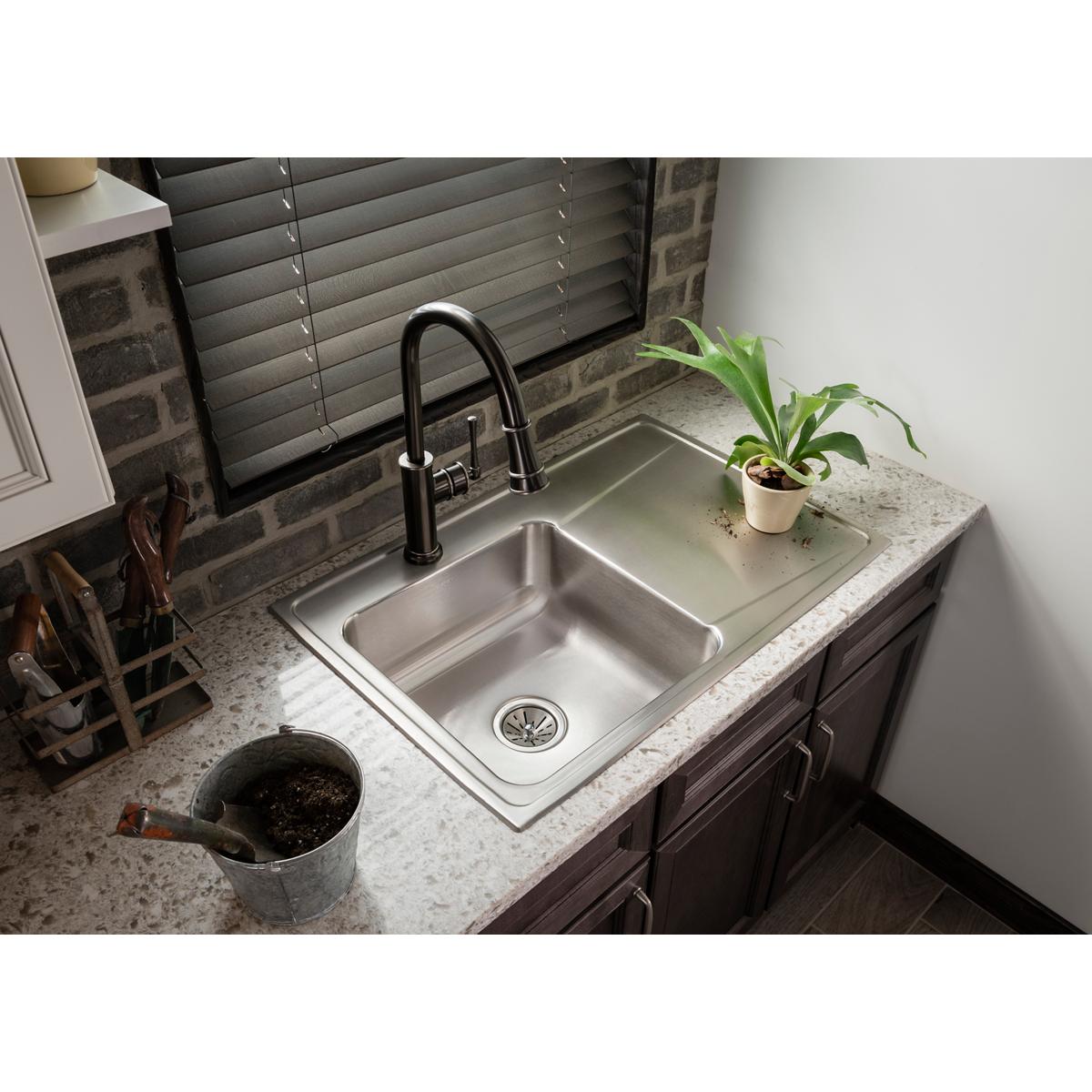 Antique steel kitchen faucet with curved spout and pull-down spray attached to single-hole sink basin.