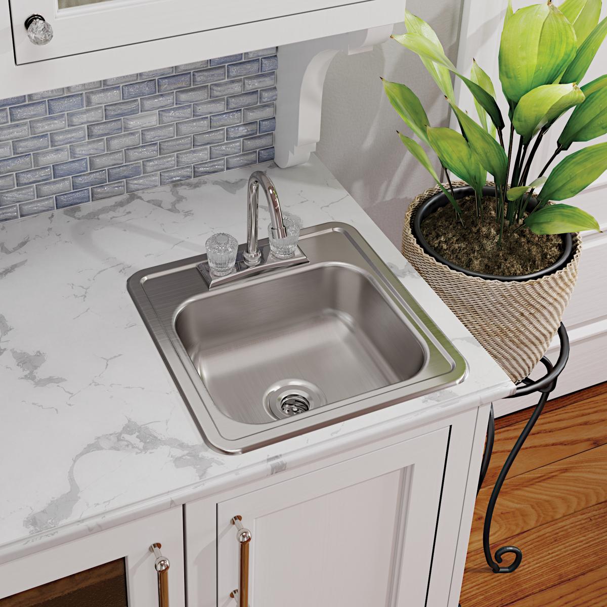 Stainless steel square sink with chrome faucet and visible drain opening installed in white countertop.