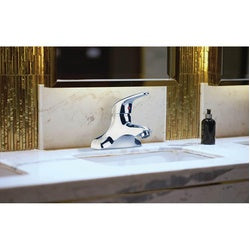 Chrome single-lever faucet with high arc spout mounted on white marble countertop.