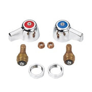 Compression repair kit with red and blue knob handles, brass valve bodies, copper seats, and metal rings arranged on white ba