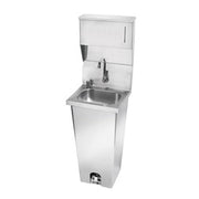 Stainless steel pedestal hand sink with foot valve, faucet, and integrated soap and towel dispensers.