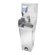 Stainless steel pedestal hand sink with foot valve, soap dispenser, and paper towel holder.