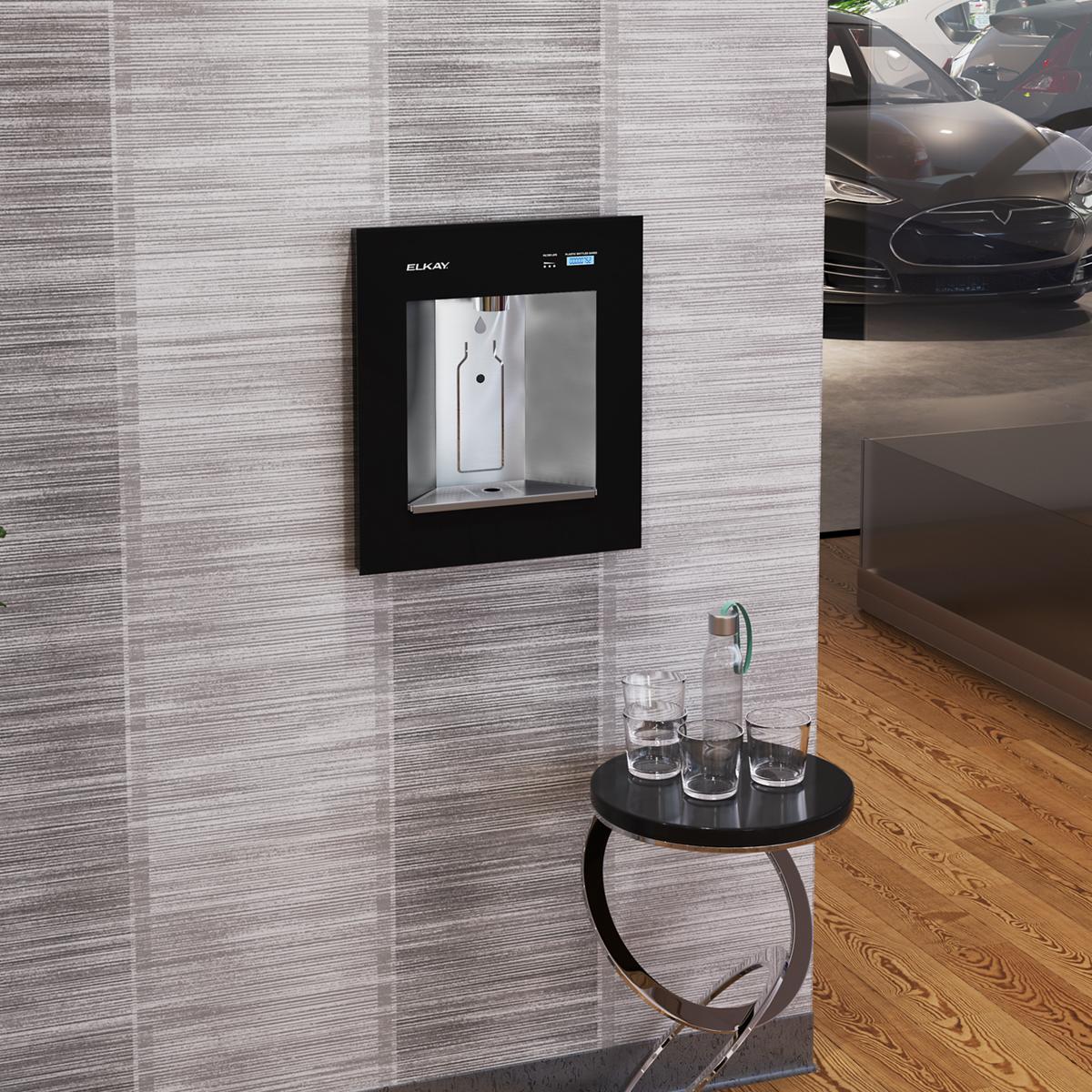 Elkay ezH2O Liv Pro midnight black in-wall water dispenser with digital display mounted on textured gray wall above black rou