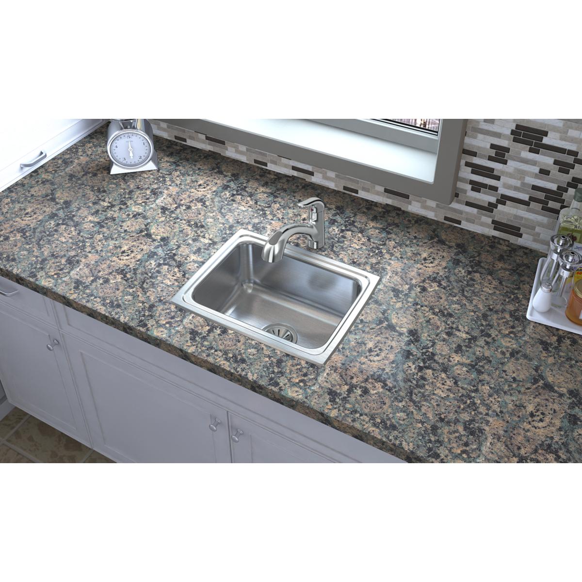 Stainless steel single bowl drop-in sink installed in granite countertop with chrome faucet.