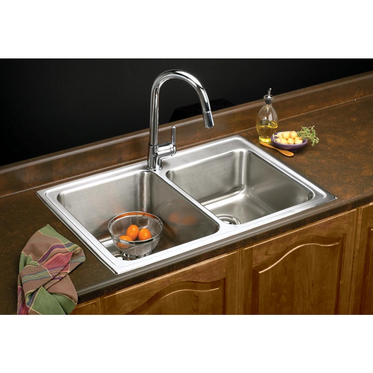 Stainless steel drop-in double bowl sink with chrome faucet installed in wood cabinetry.