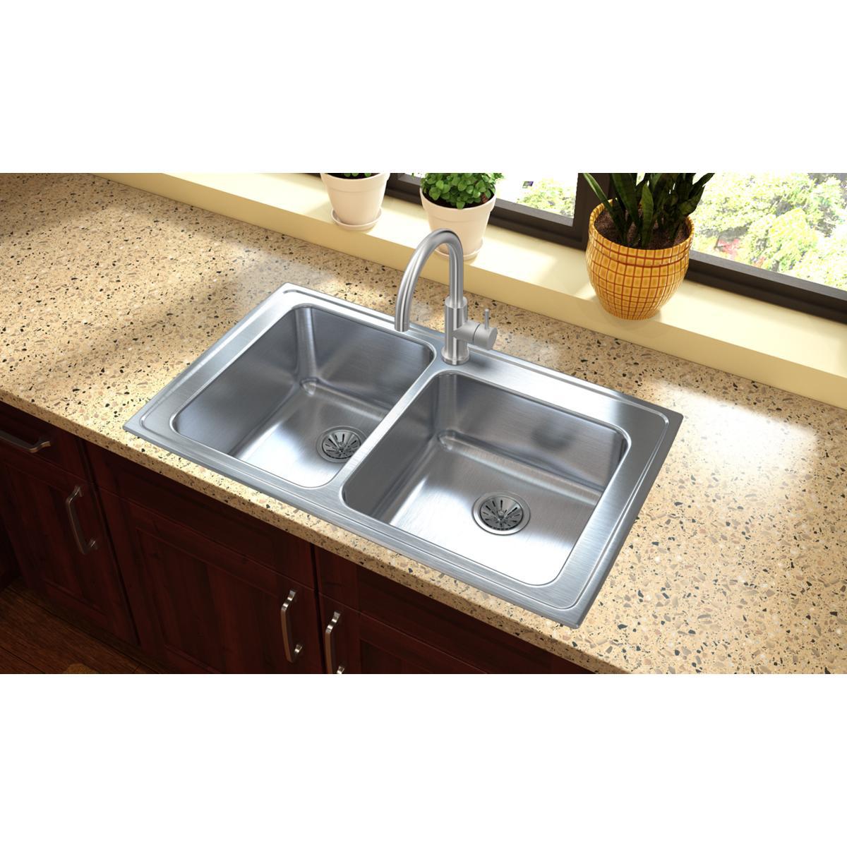 Stainless steel double bowl drop-in sink with offset design and chrome faucet installed in speckled countertop.