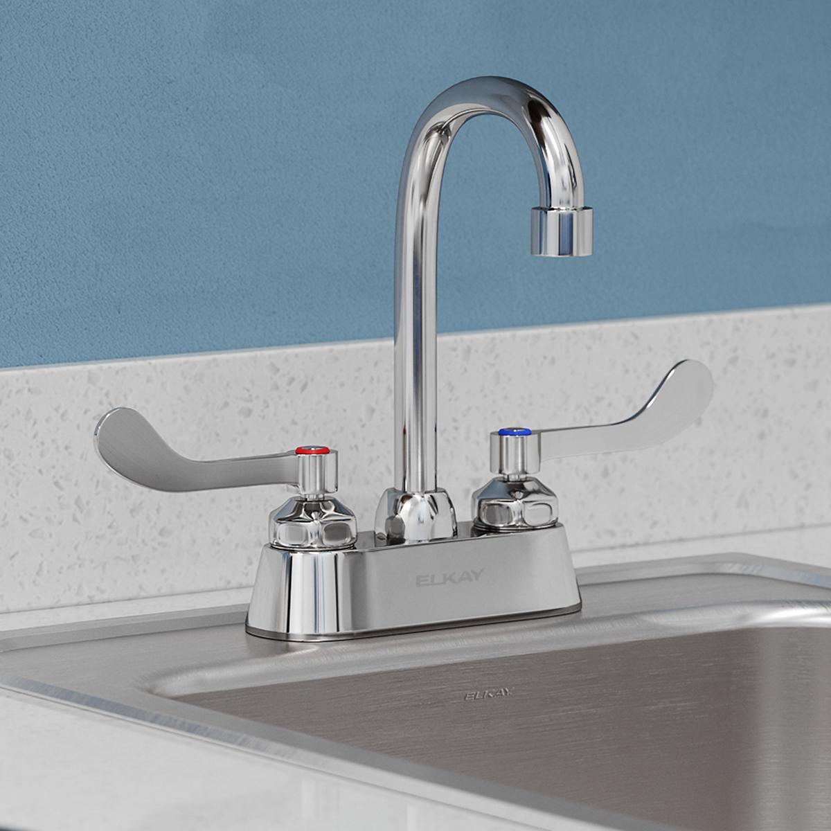 Chrome centerset faucet with gooseneck spout and wristblade handles mounted on sink deck.