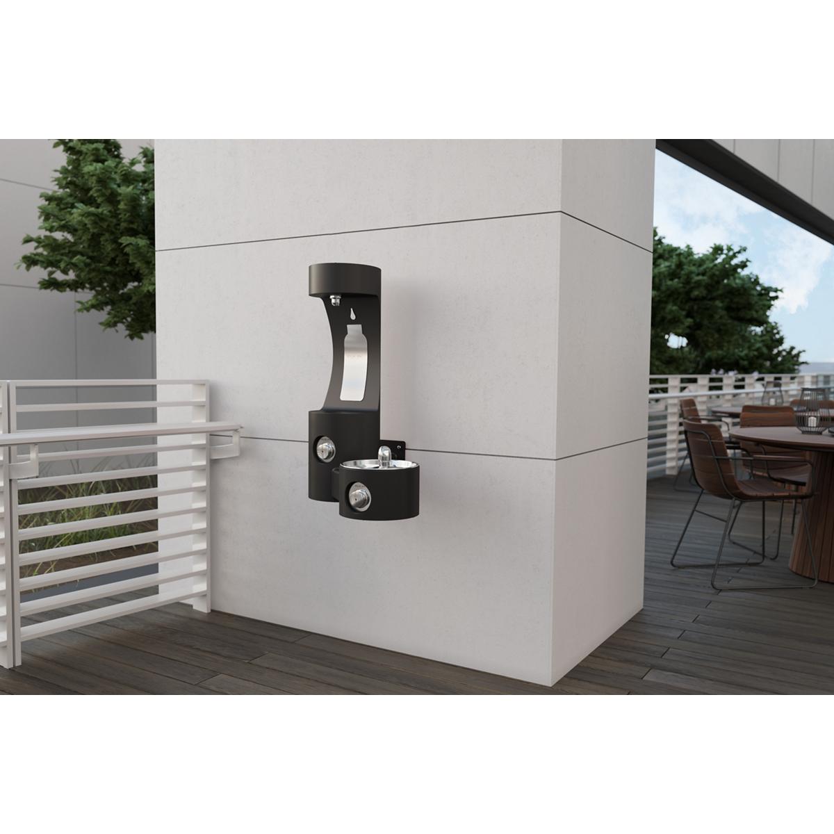 Black wall-mounted outdoor water fountain with bottle filling station and drinking spout mounted on light gray wall.