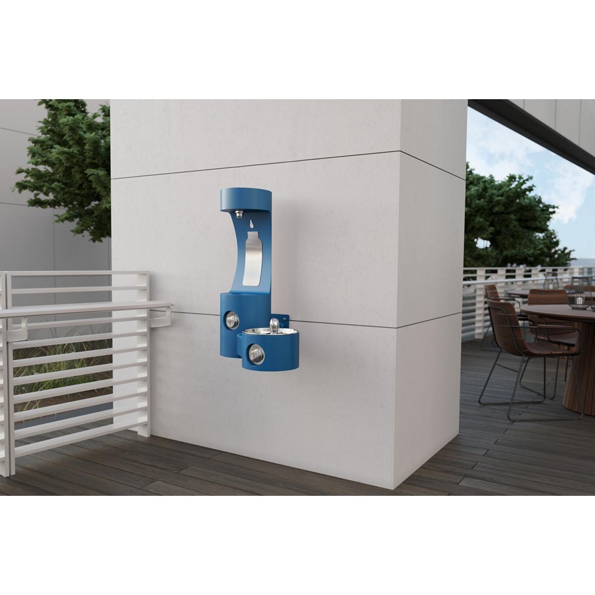 Blue wall-mounted water fountain with bottle filling station and drinking fountain mounted on concrete wall in outdoor patio 