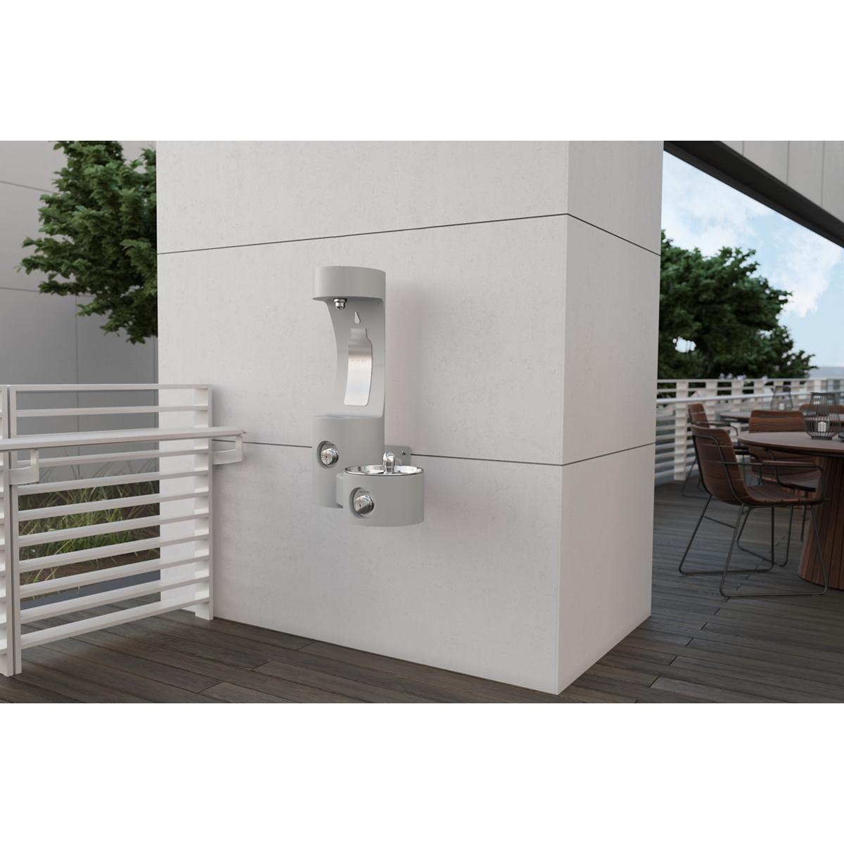 Gray wall-mounted bottle filling station with single fountain spout mounted on outdoor patio wall.