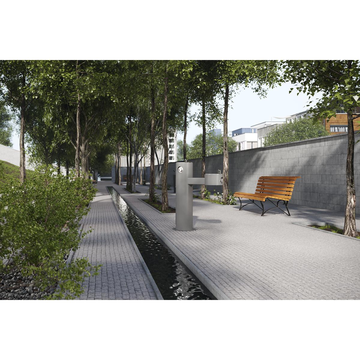 Gray pedestal fountain with two tiers installed in outdoor paved courtyard with trees and seating.