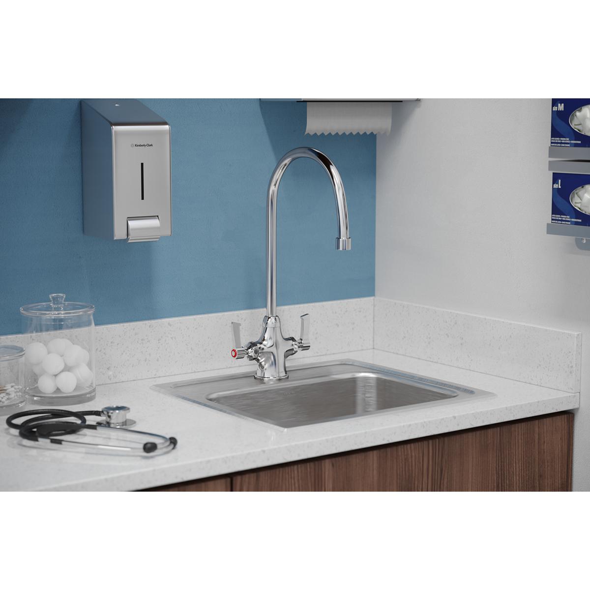 Chrome gooseneck faucet with two lever handles installed above stainless steel sink on white countertop.