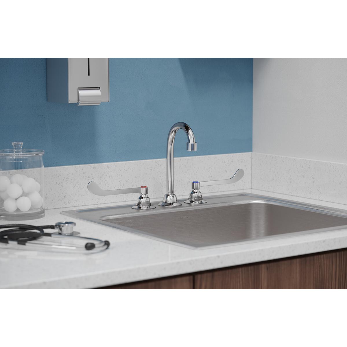 Chrome centerset faucet with curved gooseneck spout and two wristblade handles installed on white countertop sink.