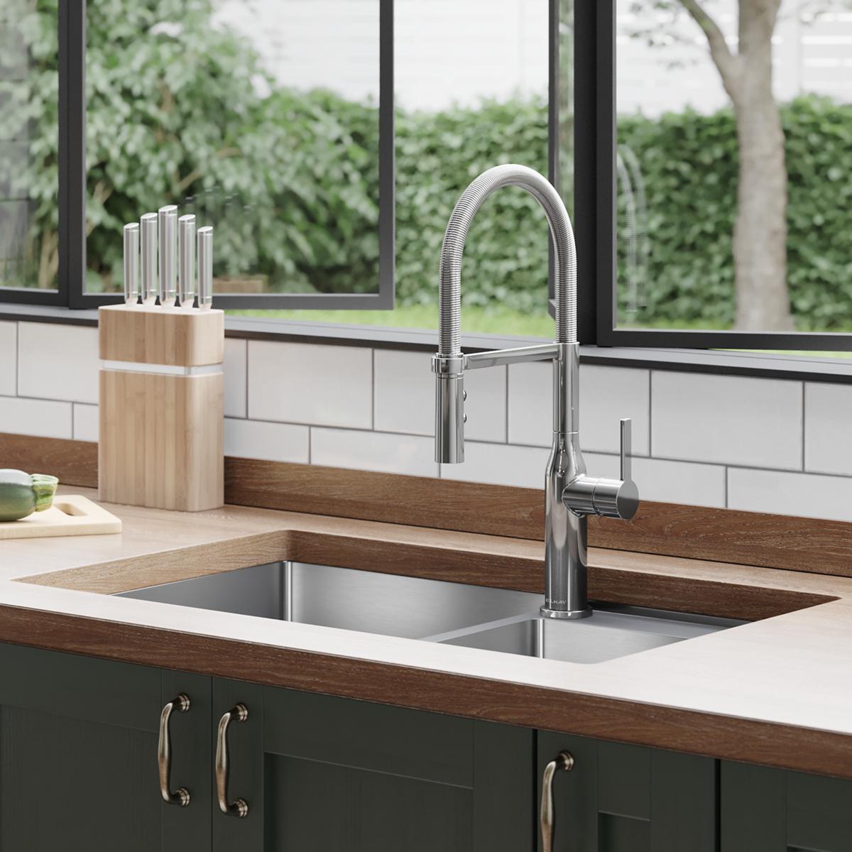Chrome kitchen faucet with curved semi-professional spout and forward lever handle mounted above double sink.