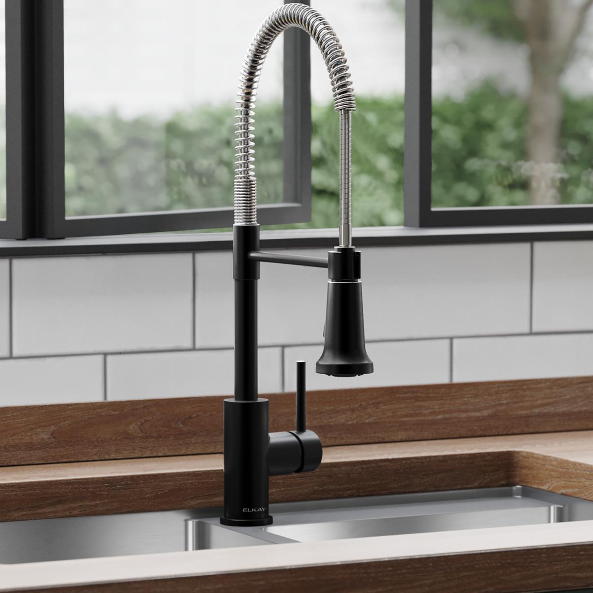Matte black and chrome single-hole kitchen faucet with flexible spray spout and lever handle mounted in sink.