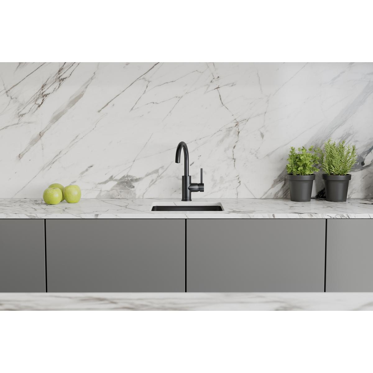 Black stainless steel single-hole bar faucet with lever handle installed on marble countertop above sink.