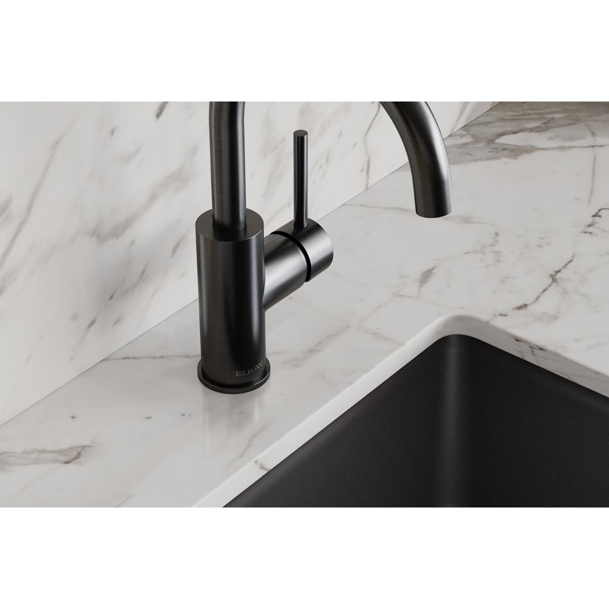 Black stainless single-hole bar faucet with lever handle mounted on marble countertop above black sink.